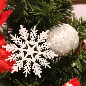 Fiocchi di neve bianchi e palline di paillettes appesi a un albero di Natale verde