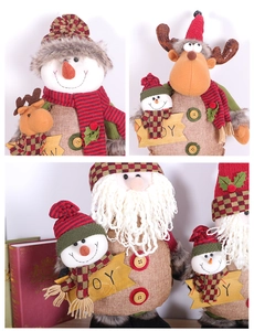 Close-up of JOY wooden sign on plush Christmas figurines with detailed fabric textures