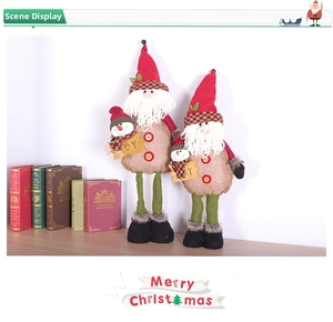 Detail of Christmas plush dolls with long legs and JOY signs on wooden tabletop