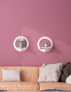 Detail showing two white round wall-mounted shelves on a pink wall for modern home decor