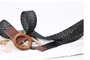 Detail of black woven belt with a round wooden buckle and brown faux leather accents