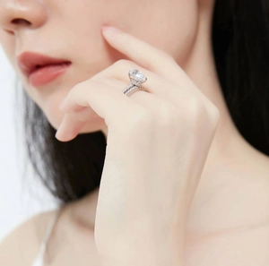 Close-up of a silver ring featuring a large oval diamond and pavé set crystals