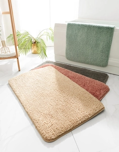Close-up of soft plush bathroom mats in beige, red, grey and green colors