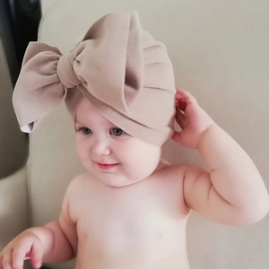 Detail of baby turban hat featuring a large 3D bow in khaki soft knit fabric