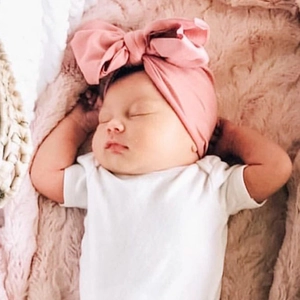 Close-up of a sleeping baby wearing a soft pink cashmere-like turban with a large bow