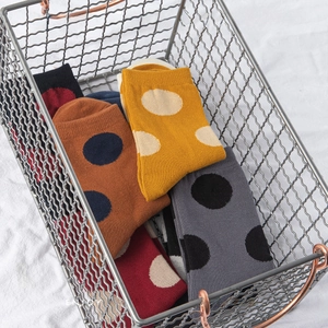 Colorful cotton crew socks with large polka dot patterns in a metal wire basket