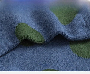 Macro shot of knitted cotton socks with dark blue base and green oversized polka dots