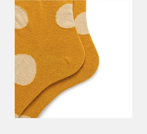 Detailed macro view of ginger yellow cotton socks with large beige polka dots pattern