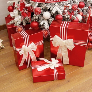 Tre scatole regalo di Natale rosse con fiocchi bianchi sotto un albero festivo