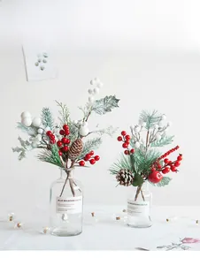 Close-up of Christmas pick with red berries, pine cones and snowballs in glass vase