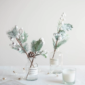 Christmas berry picks with white berries, pine needles, and pine cones in glass vase