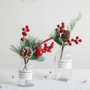 Christmas pine cone and red berry floral arrangement in clear glass bottles with warm lights