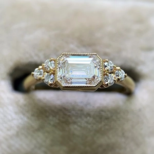 Macro shot of gold emerald-cut zircon ring with side stones in a velvet jewelry box