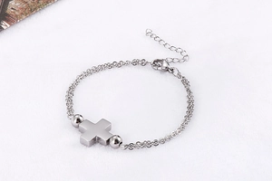 Close-up of double-layer stainless steel cross bracelet on soft white plush background