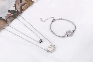 Detailed view of silver stainless steel infinity symbol necklace and bracelet set on white cloth