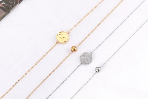 Detail of four gold and silver infinity bracelets with round charms on white fabric