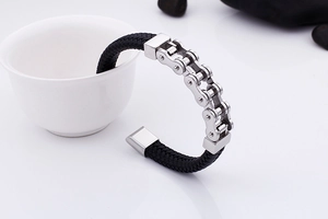 Détail d'un bracelet en cuir tressé noir avec chaîne de vélo en acier sur une tasse