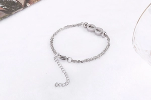 Macro detail of silver double-layer bracelet with infinity charm and lobster clasp
