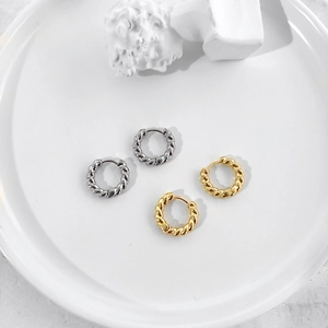 Elegant gold and silver twisted rope hoop earrings displayed on a minimalist white tray