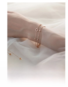 Close-up of rose gold double-layer bracelet with letter D charm worn on wrist