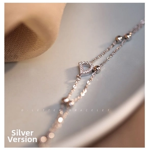 Detail of silver double-layered chain bracelet with sparkling D-letter charm