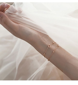 Detailed close-up of a double-layer gold bracelet featuring a paved letter D charm