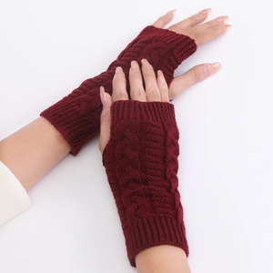 Detailed close-up of burgundy cable knit fingerless gloves with thick wool texture