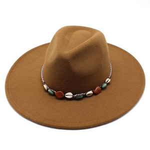 Brown wide-brim fedora hat with bohemian shell and gemstone band on white background