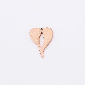 Macro detail of rose gold heart angel wing pendant with delicate feather textures