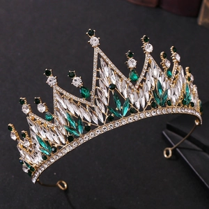 Macro shot of gold tiara with emerald green and clear crystals on dark background