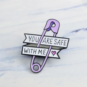 Purple safety pin enamel pin featuring 'YOU ARE SAFE WITH ME' text and a small heart