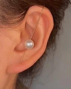 Close-up of minimalist gold needle earrings with a sleek bar design and white pearl detail