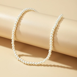 Elegant single strand round pearl necklace for women with soft silk luster on warm pedestal