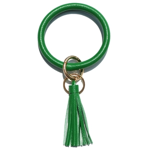 Detail of green python pattern leather keychain bracelet with tassel and gold metal hardware