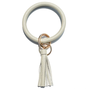 Detail of sage green lychee textured leather wristlet with golden ring and tassel charm