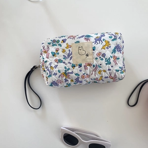 Dettaglio di una trousse bianca trapuntata con stampe colorate di fiori e cervi