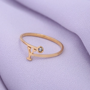 Detail van de gouden ring met letter Y en een zirkonia steen op een zachte stof
