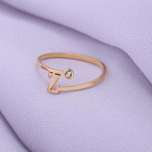 Macro-opname van gouden ring met letter Z en zirkoon op paarse getextureerde stof