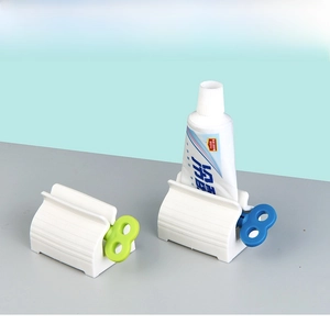 Manual toothpaste squeezer roller with colored knobs showing base and tube application