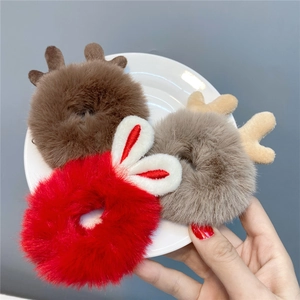 Plush Christmas reindeer antlers and red bunny ears hair ties shown on a white plate