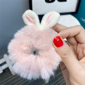 Close-up of a pink plush scrunchie with cute bunny ears held in hand for detail