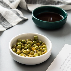 Japanese ceramic dipping dish with seasoned green peas on a minimalist plaid napkin