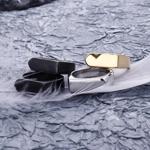 Detail of geometric square rings in gold, silver, and black finishes on a white feather