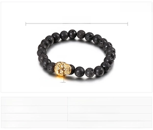 Détail des perles en pierre volcanique noire et du crâne doré sur le bracelet élastique