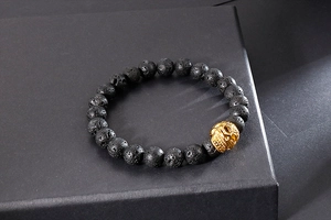 Vue détaillée des perles de pierre de lave avec un pendentif tête de mort doré