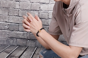 Détail d'un bracelet en perles noires mates avec un charmant Pixiu doré poli dessus