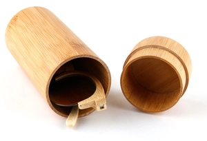 Detail view of a cylindrical bamboo case with handmade wooden sunglasses inside