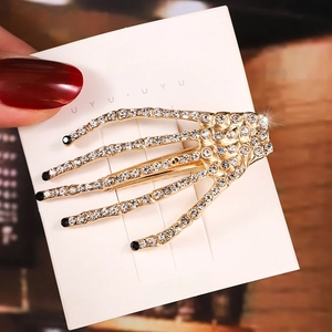 Detail of golden skeleton hand hair clip with sparkling rhinestones on card