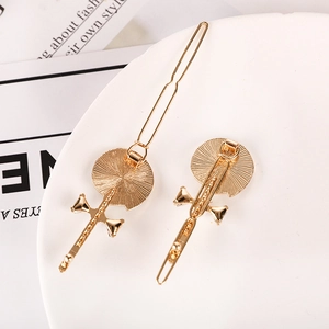 Close-up of two golden alloy hair clips with bow designs and circular textures