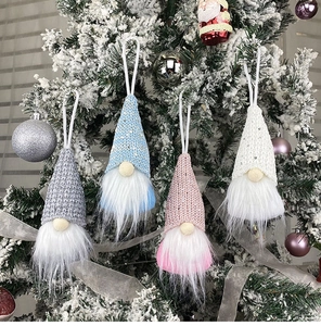 Detailed view of four colorful sequined Christmas gnomes hanging on a snowy Xmas tree